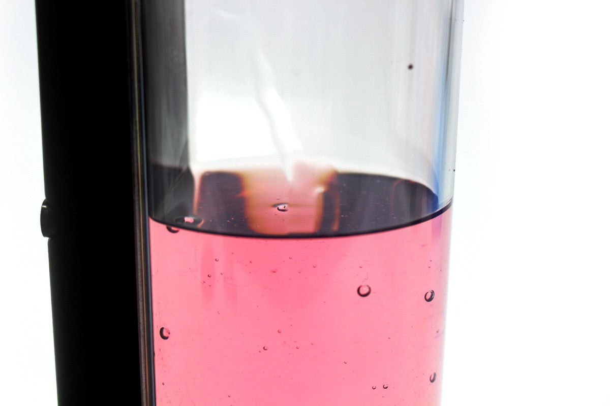 Close-up of the automatic soap dispenser’s transparent reservoir containing pink liquid.