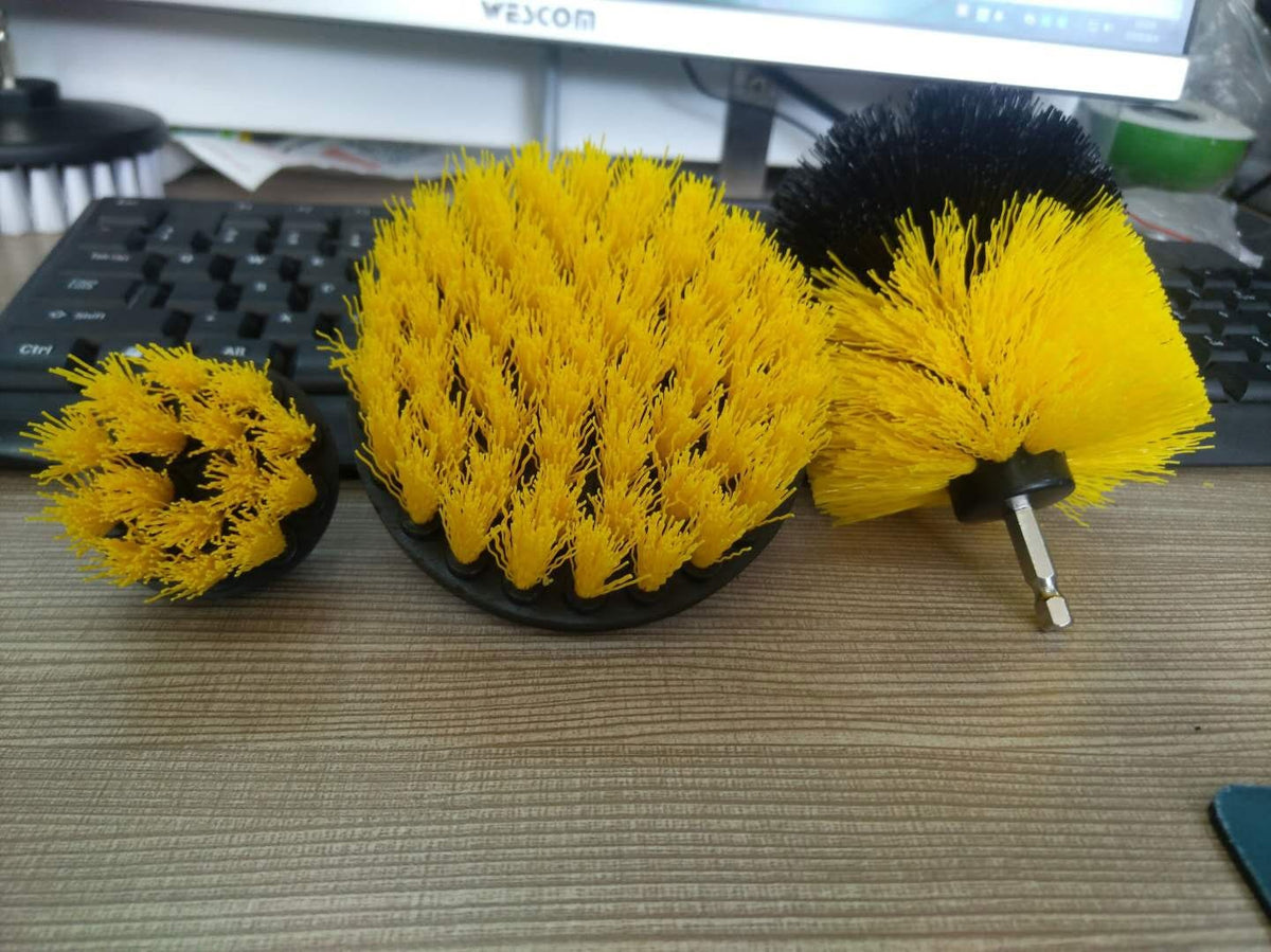 Three drill cleaning brushes resting on a desk, showing yellow bristles and the rounded brush’s black tip.