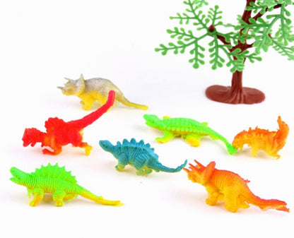  Assorted colorful toy dinosaur figures arranged on a white surface beside a decorative toy tree.
